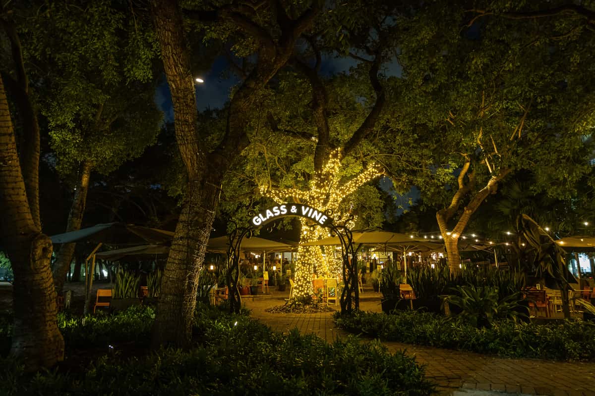 Romantic anniversary dinner venue entrance in Miami illuminated with warm lights and surrounded by lush greenery.