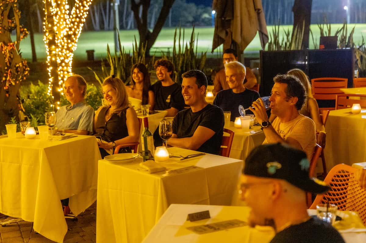 Guests seated at tables enjoying drinks during an outdoor engagement dinner party.