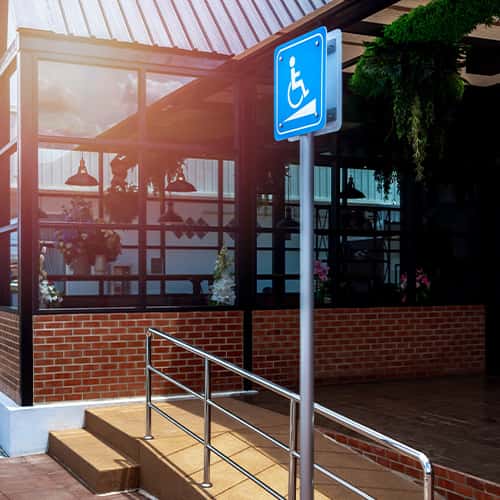 ADA-compliant restaurant entrance ramp with proper handrails and accessibility signage demonstrating correct slope and width specifications