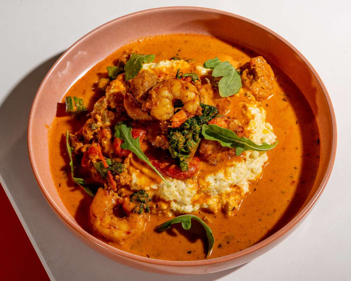 Shrimp and grits served in a creamy sauce with greens and vegetables.