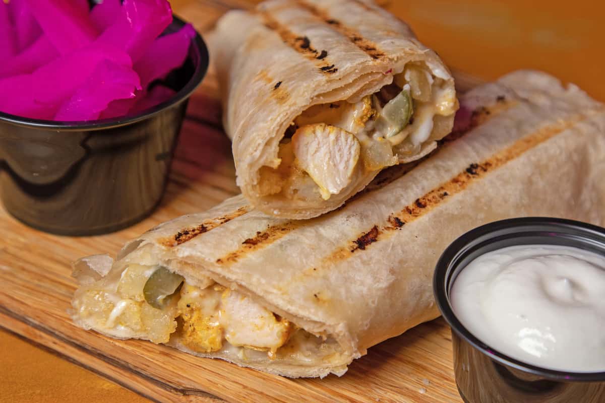 Chicken kabob wrap sliced in half, served with a dipping sauce