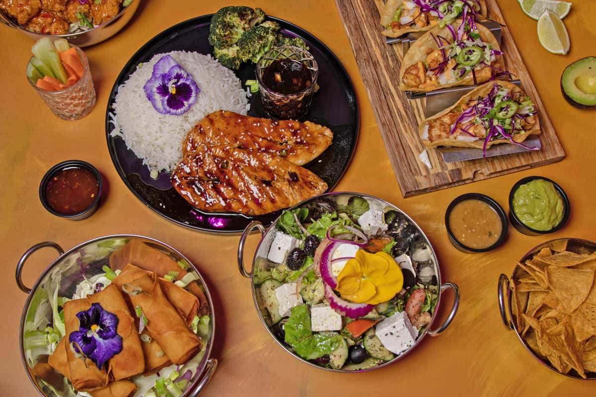 Assorted plated dishes including grilled meat, rice, and salad