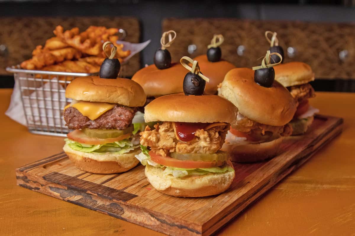 Chicken and beef sliders stacked on a wooden serving board
