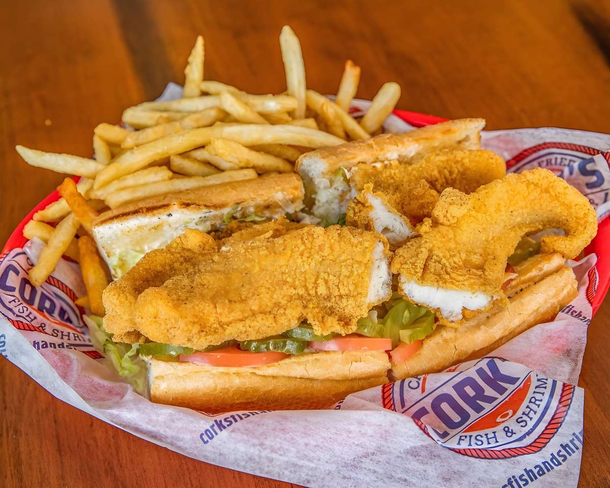 Fried fish po' boy sandwich served with French fries.