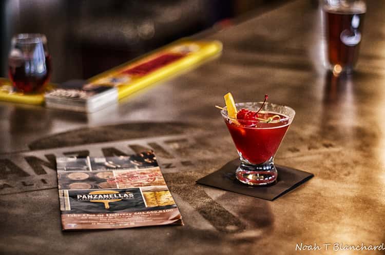 Image of a drink sitting on a bar next to a menu