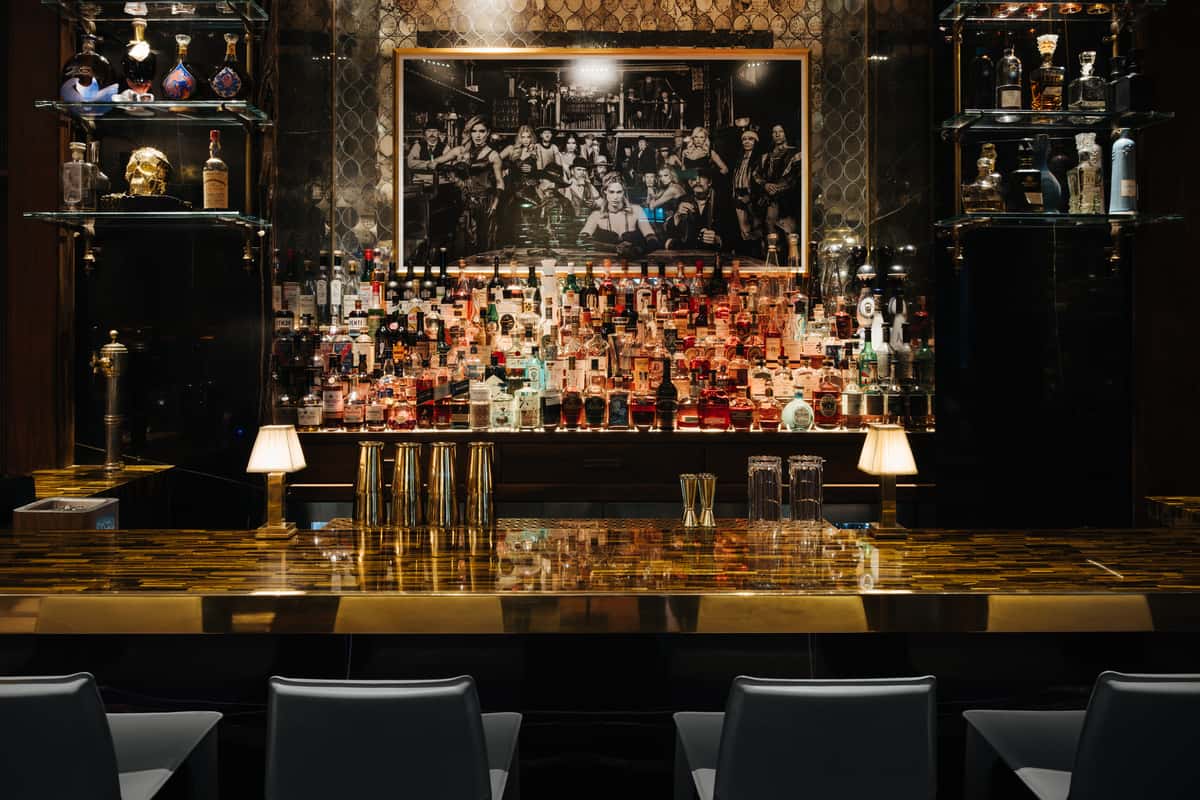 Interior bar scene with bottles and glassware behind the counter.