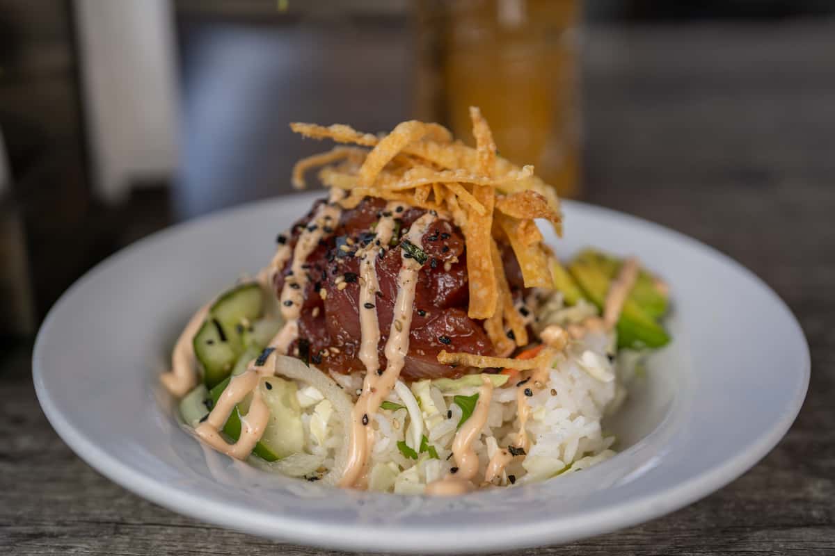 ahi tuna poke bowl with white rice, cucumber, avocado, crispy wonton strips, and spicy mayo drizzle