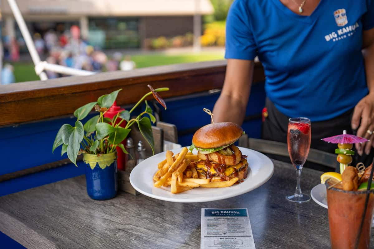 gourmet burger with melted cheese, crispy onions, and fries served on a waterfront restaurant patio
