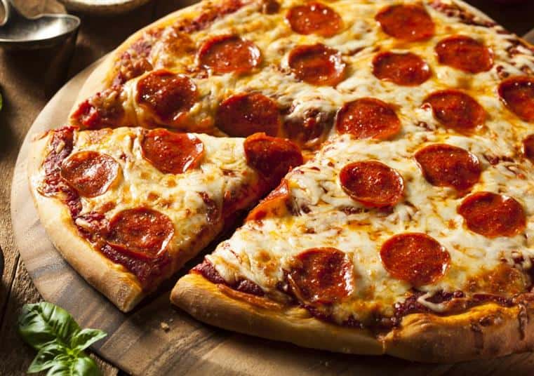 Pepperoni pizza with one slice cut on wood board.