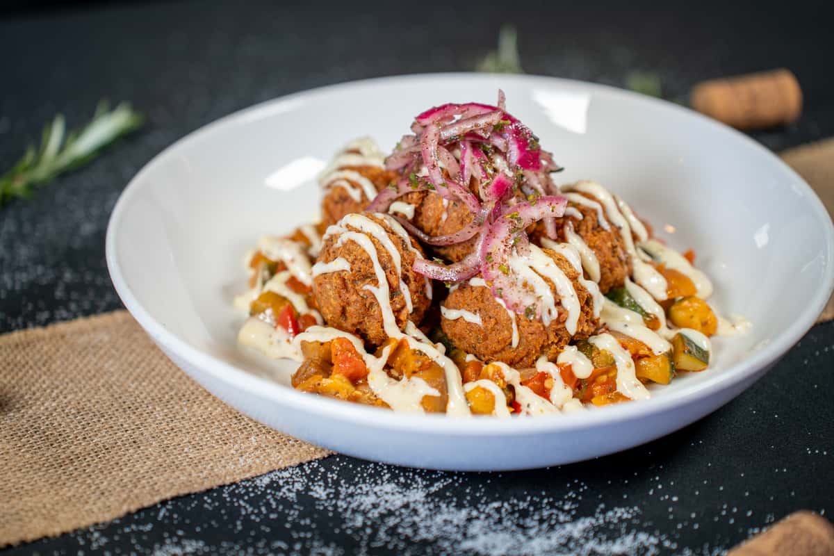 Experience the delightful flavors of our Falafel at Black+Haus Tavern, a beloved gastropub offering craft beer and dining in Parker, Colorado, and Littleton, Colorado. This gluten-free and vegan dish features haus-made chickpea fritters served with a medley of ratatouille, tangy sumac onions, and a creamy garlic aioli. Perfect for those seeking vegetarian or vegan dining options, our Falafel provides a satisfying and flavorful meal. Whether you're looking for fine dining experiences or casual dining spots in Littleton or Parker, our tavern offers a warm and inviting atmosphere for all occasions. Whether you're searching for local cuisine, outdoor dining restaurants, or the best happy hour deals, Black+Haus Tavern is your go-to destination for quality dining in Colorado.