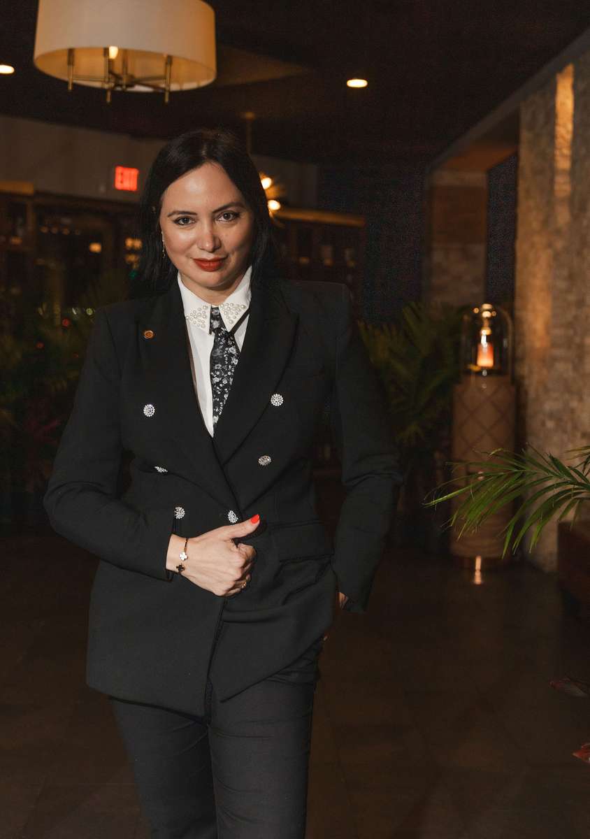 Woman in polished formal attire at an upscale Coral Gables restaurant.