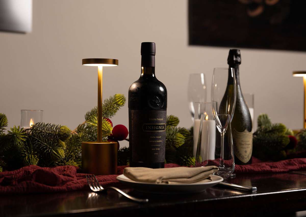 Premium wine and champagne bottles complement an elegant private party table setting with warm lighting and seasonal greenery.
