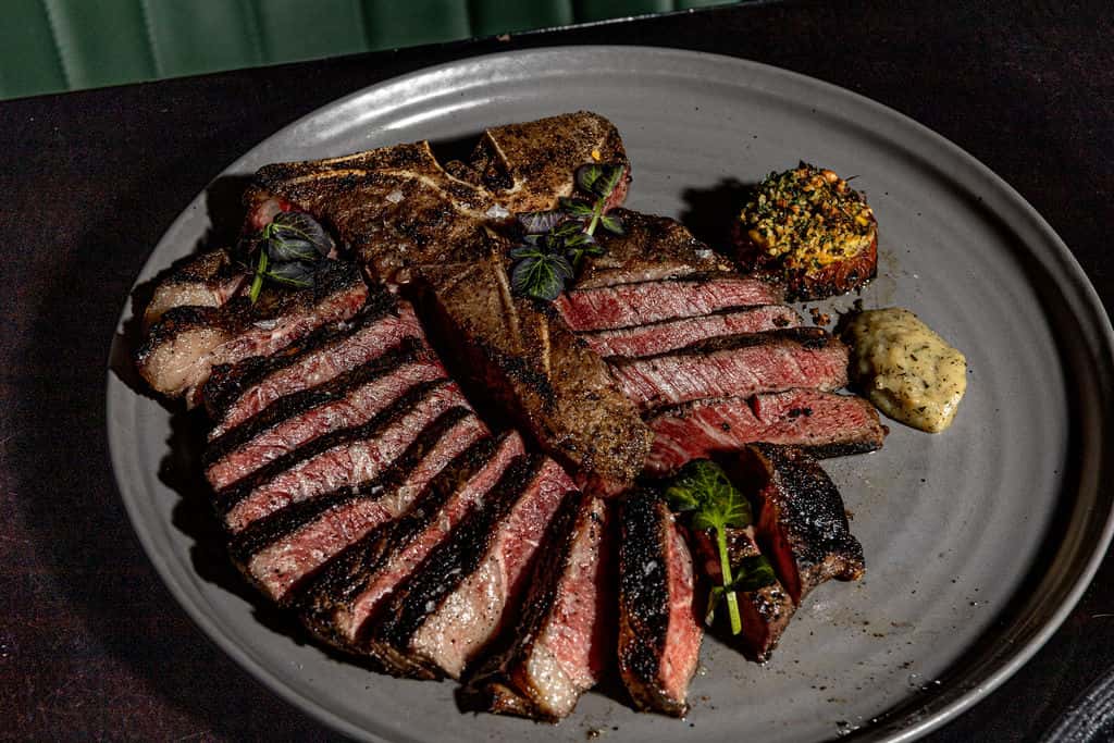 Sliced porterhouse steak cooked medium rare and served with sauce.