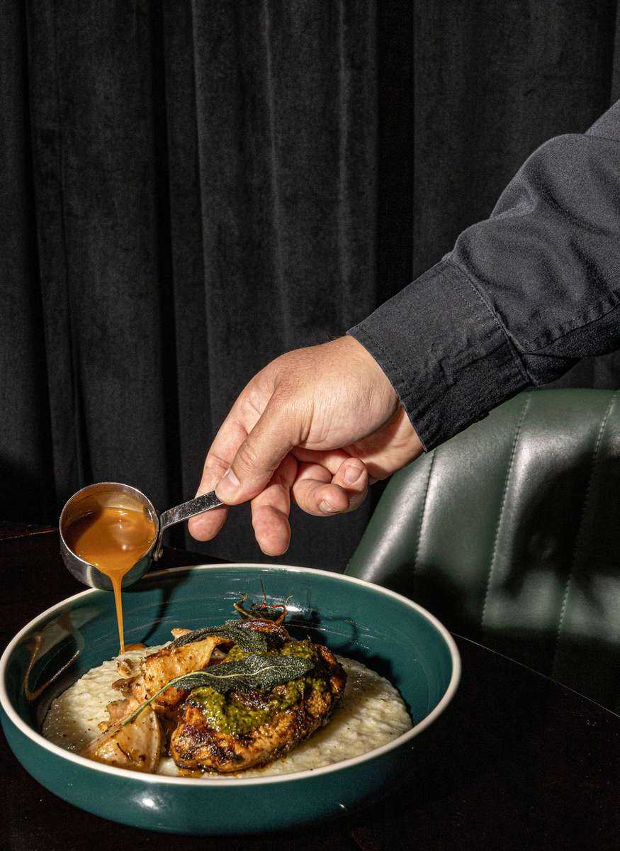 Sauce being poured over grilled steak served with creamy sides.