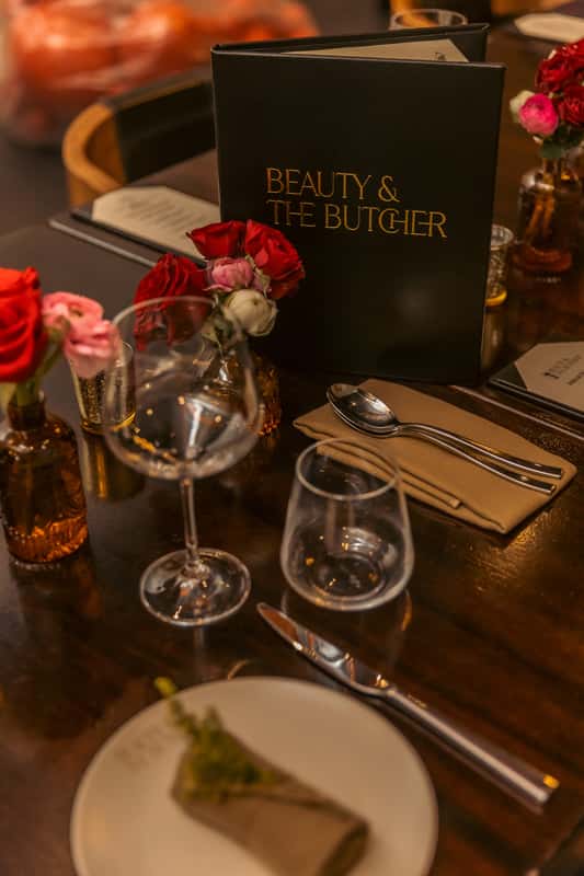table with wine glasses, roses, and menu