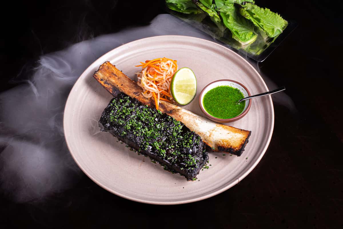 Braised beef short rib served with fresh herbs, slaw, lime, and green sauce, illustrating cooked meat after frozen storage.