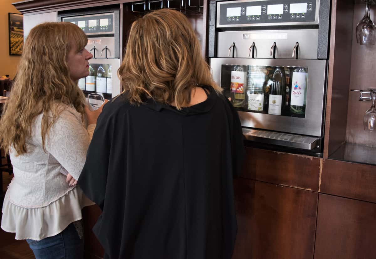 Women using the wine bar taps