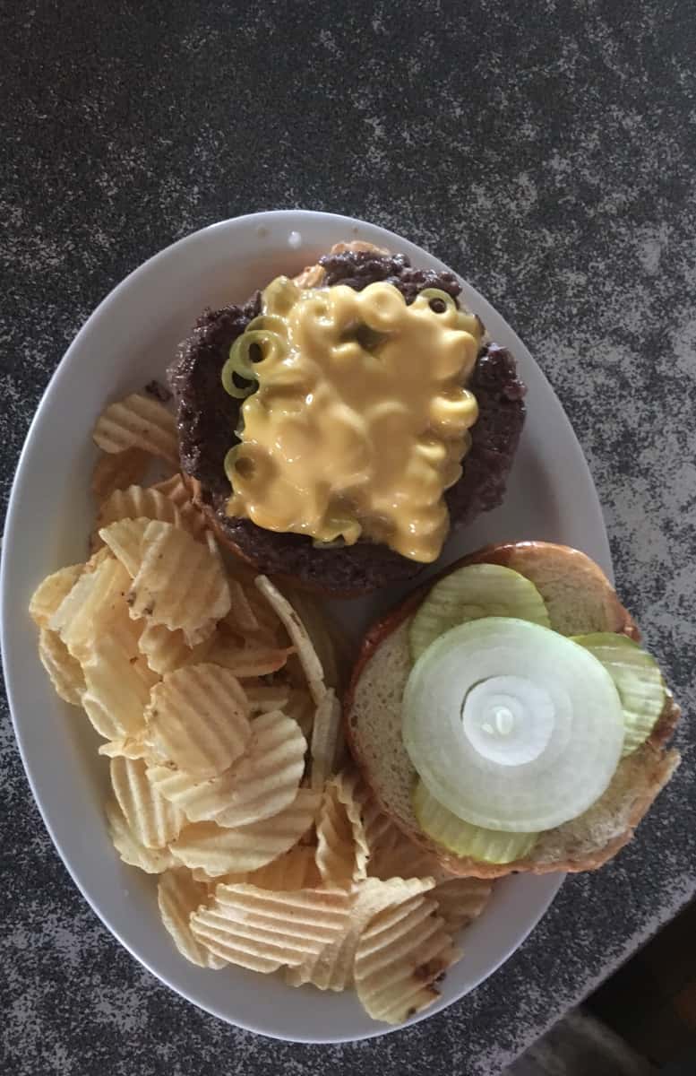hamburger topped with cheese with potato chips on the side