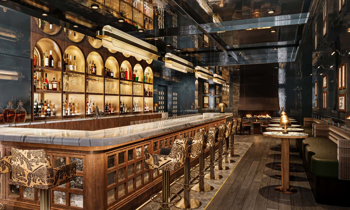 Luxurious bar with a marble countertop, patterned bar stools, arched backlit liquor shelves, and a cozy fireplace seating area.