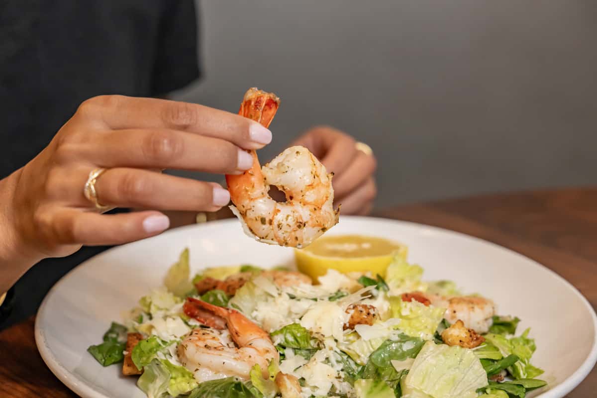 Woman holding a prawn from her meal