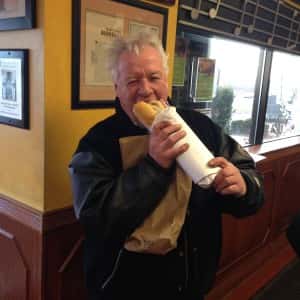 man inside the restaurant biting into a sub sandwich