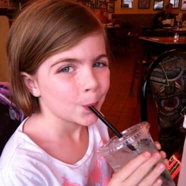 little girl drinking a cup of water through a straw