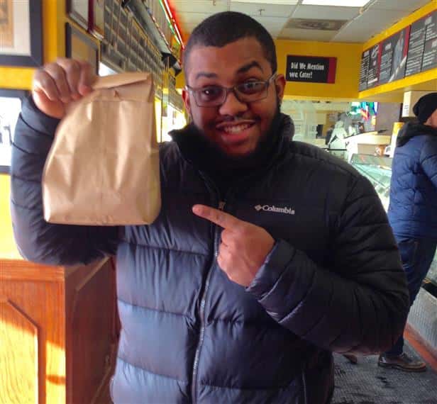 customer smiling inside the store holding up a take out bag