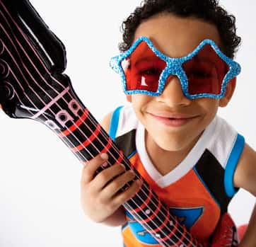 little boy wearing star sunglasses and playing a blow up guitar