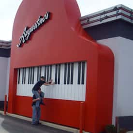 child sitting on someone's shoulders playing the large decorative piano on the outside of the building