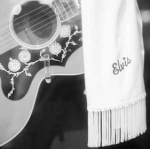 guitar with a scarf hanging over that says "Elvis"