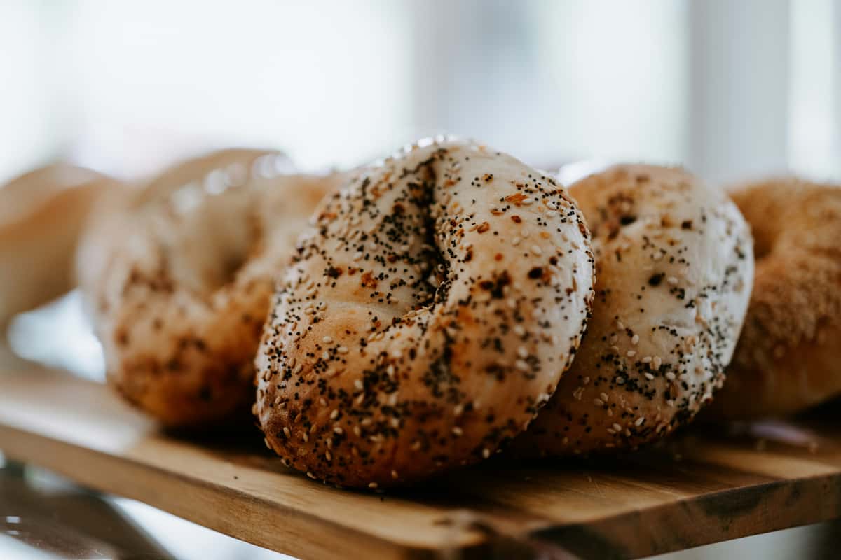Close-up of everything bagels topped with poppy and sesame seeds on a wooden board.