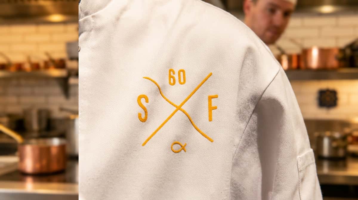 Close-up of a Sixty Fish staff uniform featuring the restaurant's embroidered logo.