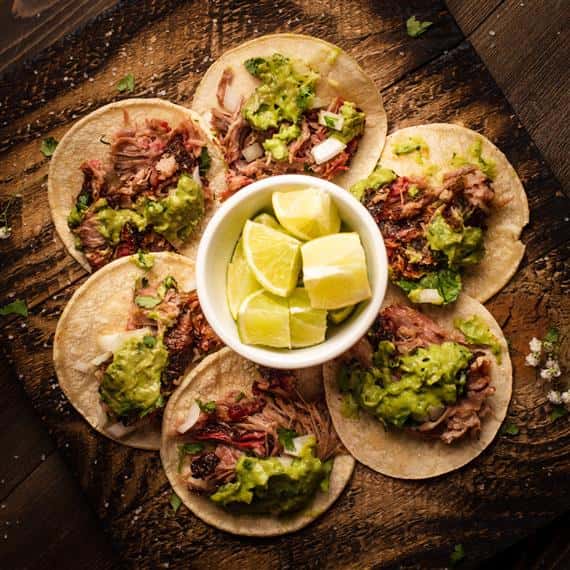 soft shell tacos on a wood table with lime wedges in the center