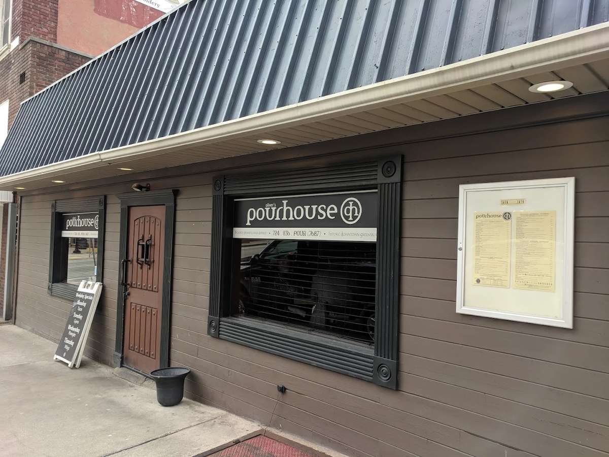 Exterior view of Oliver's Pourhouse with dark trim, wood-paneled facade, and visible logo signage above front windows.