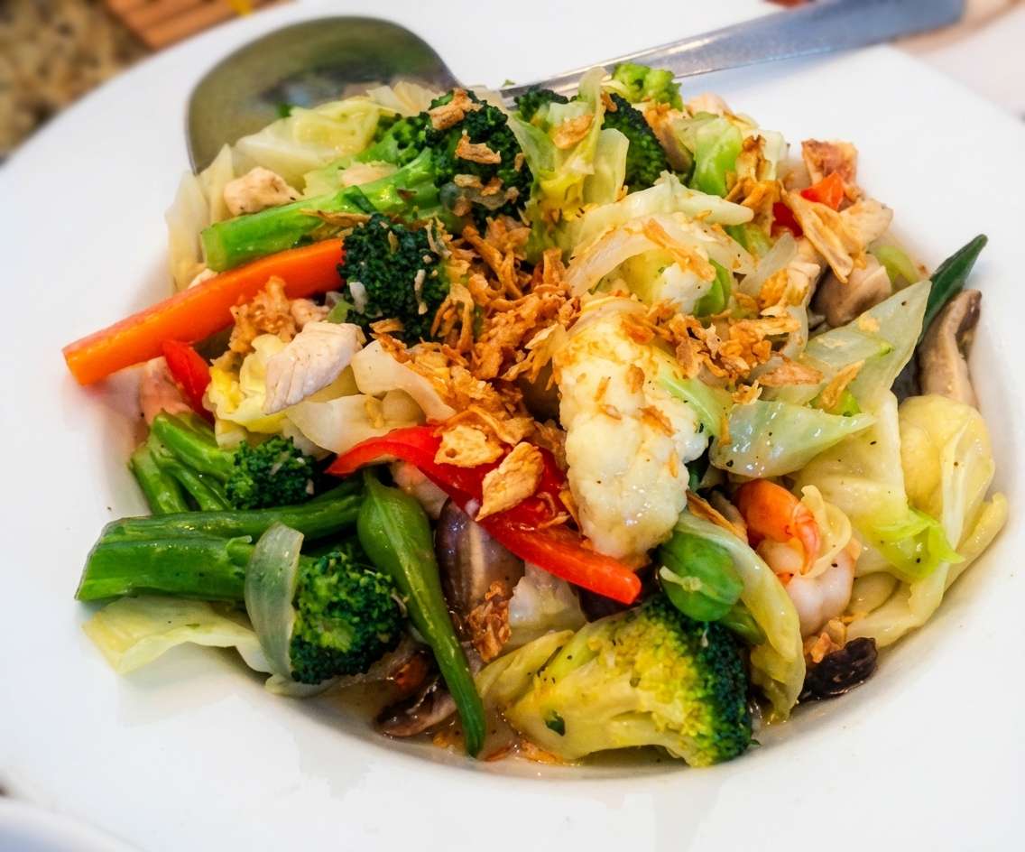 A colorful stir-fry of fresh vegetables including broccoli, cabbage, carrots, and greens, tossed with herbs and sesame seeds for a vibrant and healthy dish.
