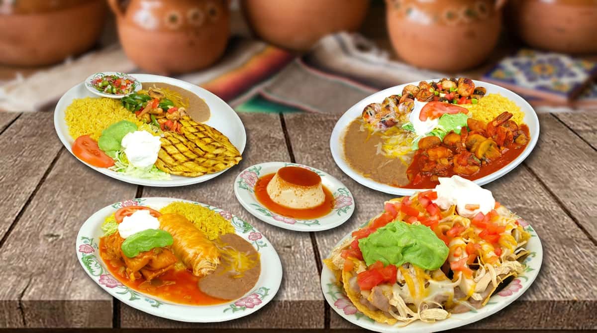 A spread of authentic Mexican dishes arranged on a wooden table, featuring enchiladas, rice, beans, guacamole, and fresh garnishes. Each plate is rich in color and texture, showcasing generous portions and traditional flavors, perfect for sharing in a warm, inviting dining setting.
