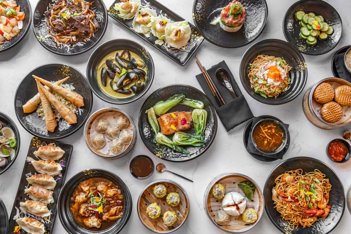 A vibrant spread of various Asian Seafood and Asian-fusion dishes artfully arranged on a table.