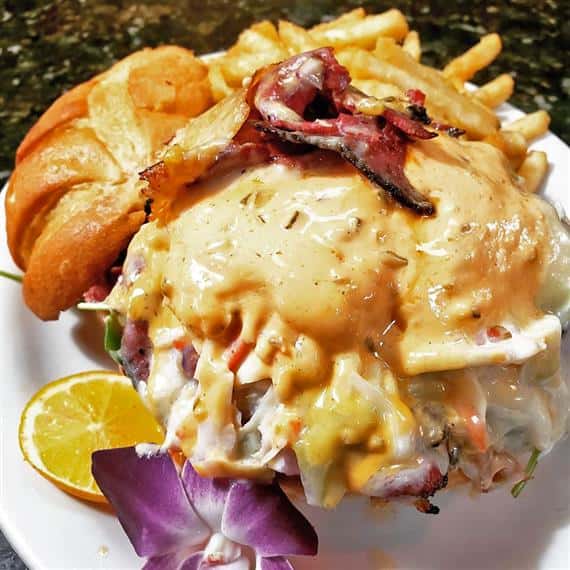 open faced roast beef sandwich topped with hollandaise sauce and a side of fries