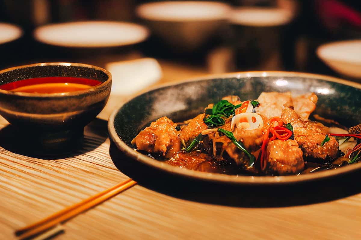 Chinese-style dish with chicken, vegetables, and sauce served in a pan.