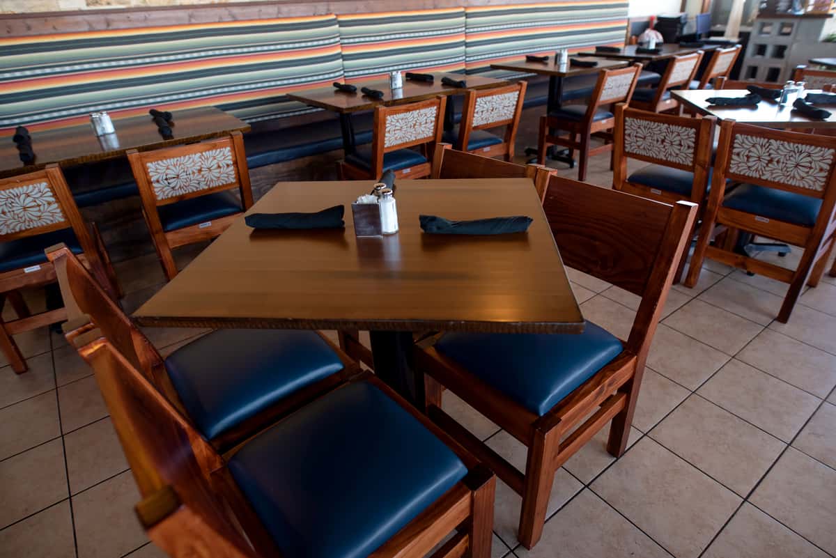 outdoor waterfront restaurant table setup with wooden chairs and scenic marina views