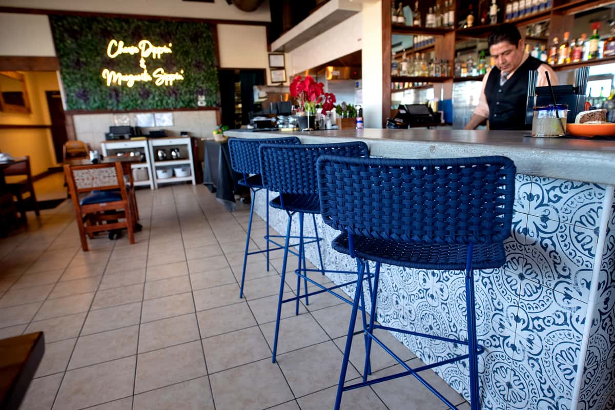 open-air restaurant bar with blue stools, casual seating, and a relaxed coastal dining atmosphere