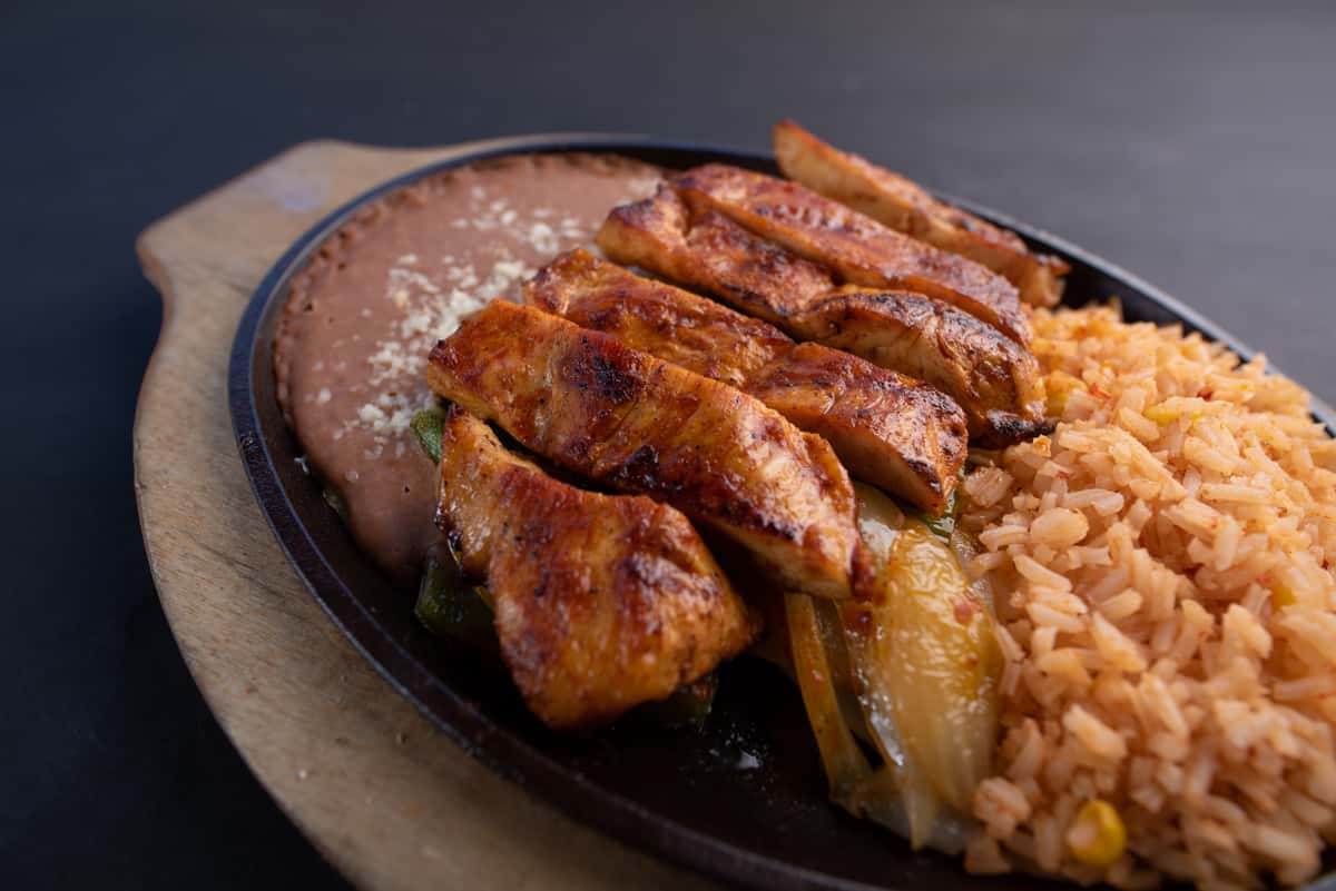 sizzling chicken fajitas with grilled onions and peppers served on a hot skillet with rice