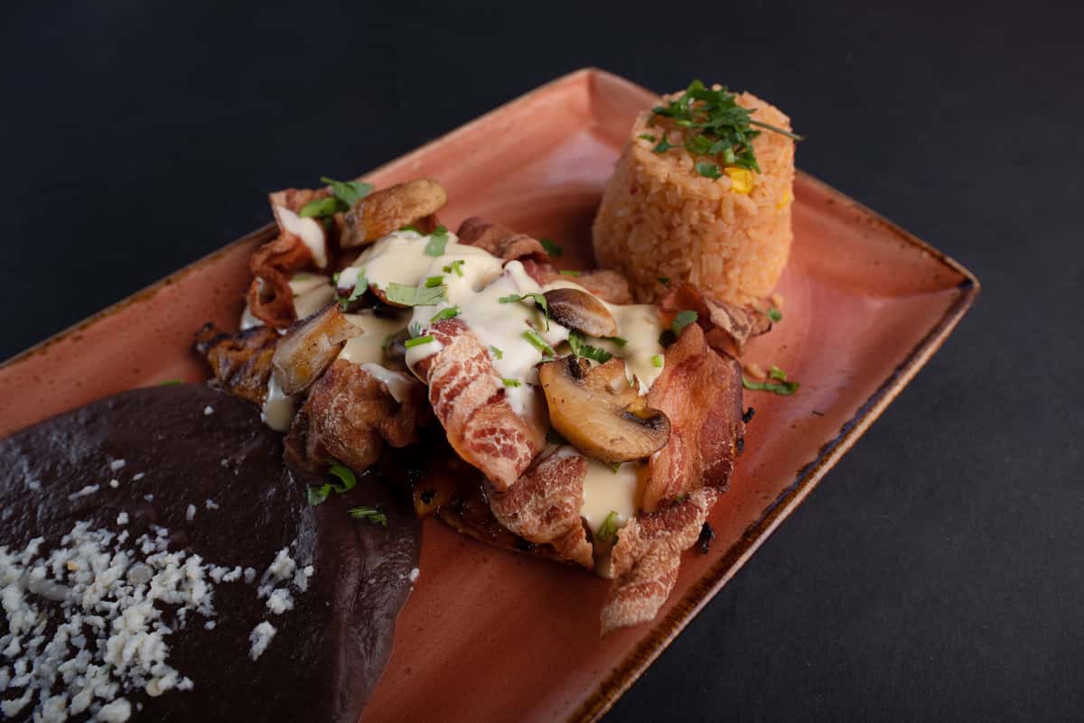 grilled chicken platter with roasted potatoes, rice, and creamy sauce on a rustic serving tray