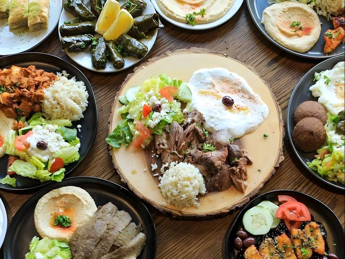Mediterranean spread featuring hummus, falafel, grilled meats, rice, salads, and fresh vegetables.