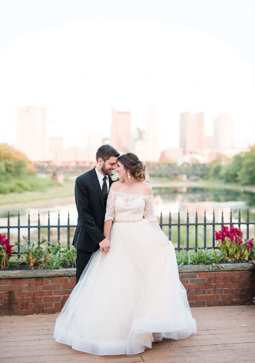 Bride and groom intimately embrace for photographs at The Boat House in front of the skyline river view.