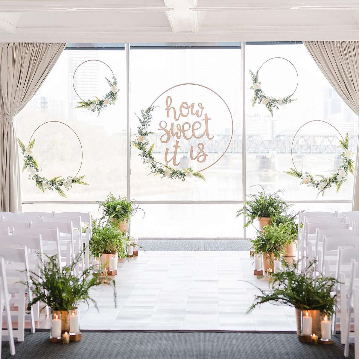Columbus indoor wedding space with a floor to ceiling window wall decorated with wreaths and greenery.