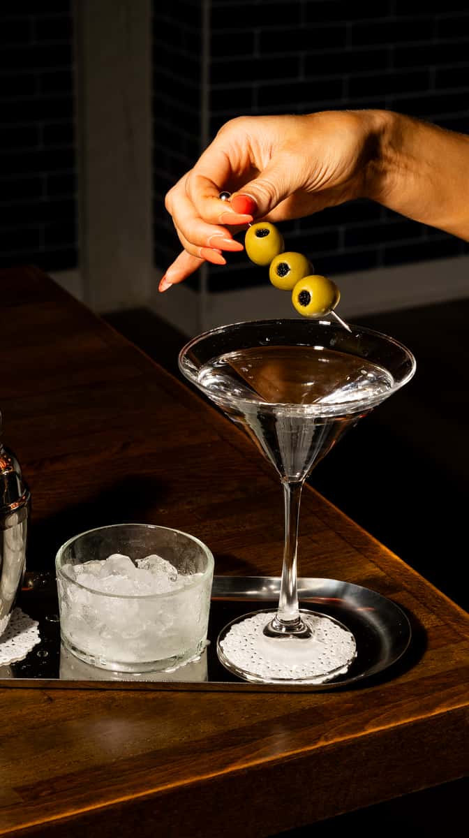 Classic martini with olive garnish served in an elegant cocktail glass at a dimly lit upscale restaurant bar