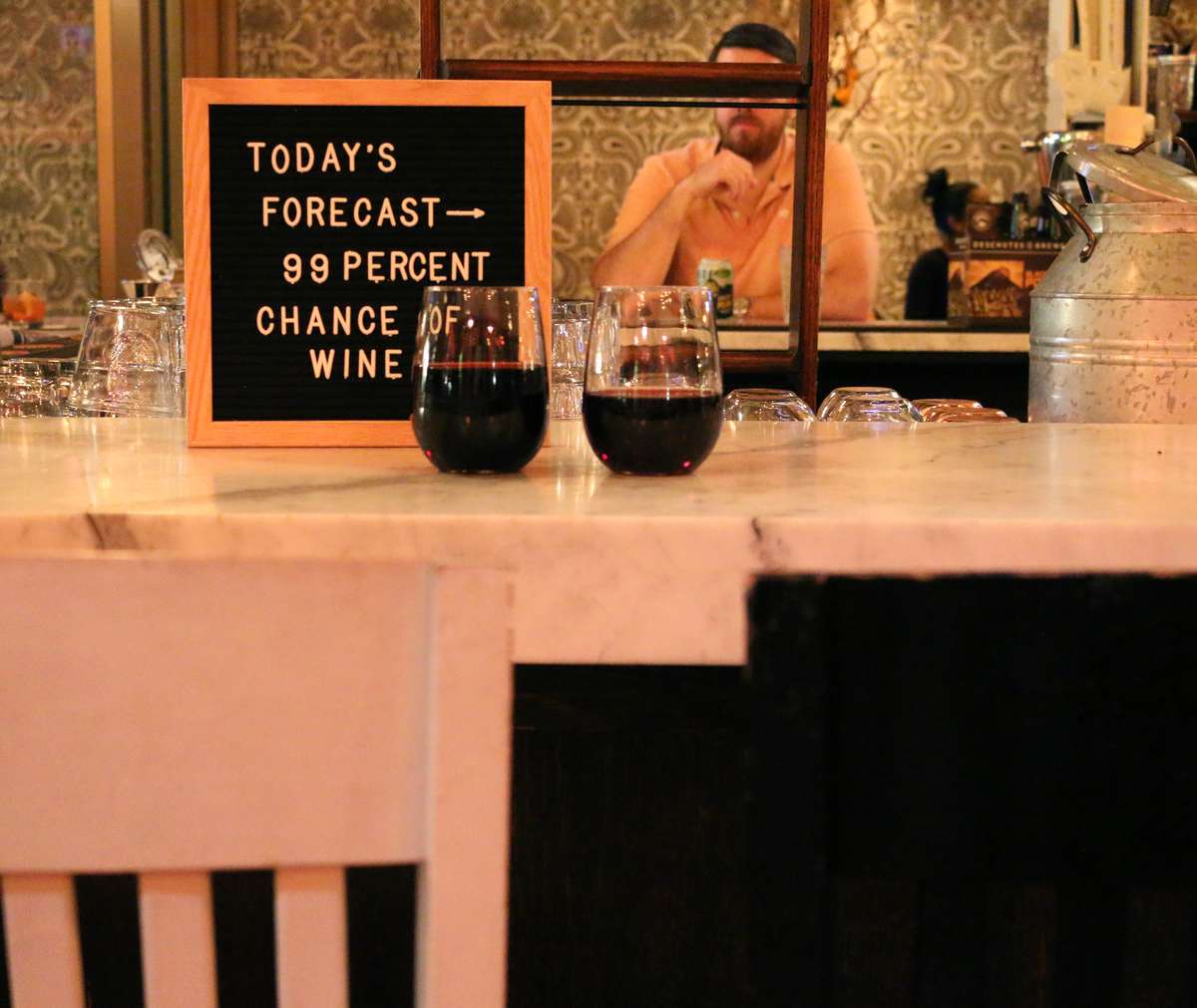 two wine glasses on table with sign