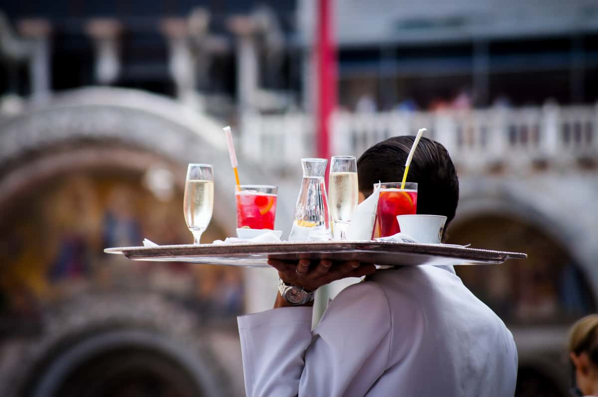 Waiter carrying a tray of drinks to a table