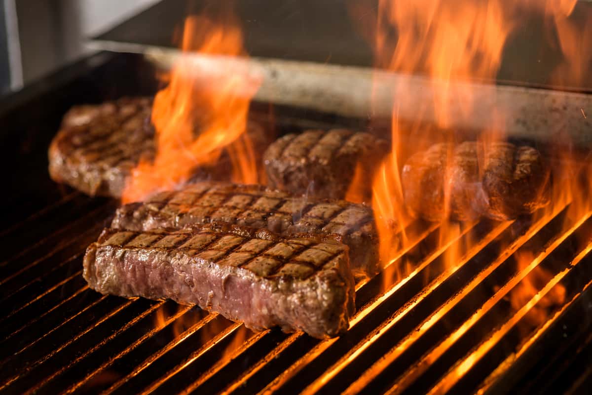 Sirloin cooking on grill, flames
